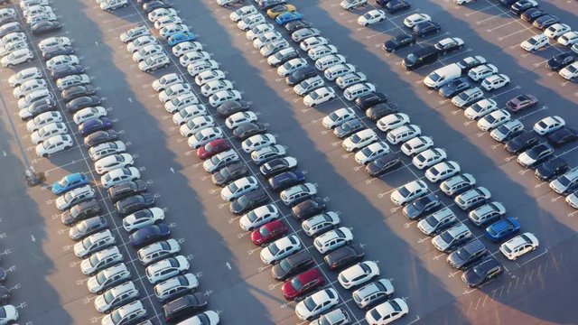 Aerial top view of the dealership terminal parking lot with a rows of new cars on a sunny day