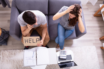 Couple Holding Help Sign While Calculating Invoice