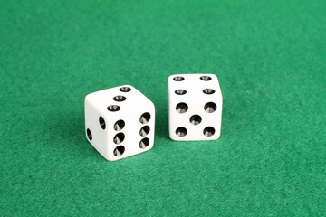 Pair of white dice on green felt with winning numbers seven and eleven showing