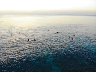 Aerial view of surfers on their board waiting the waves during sunset, big waves tropical blue ocean, drone view of surfer catching the blue waves, Bali, Indonesia