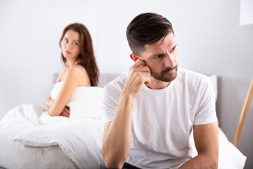 Depressed Man Sitting On Bed