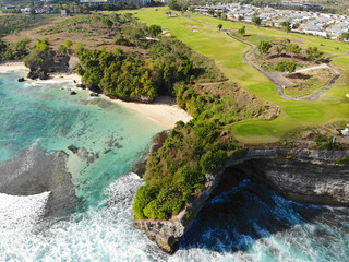 Aerial view luxury golf field next the cliff, ocean and beach in Bali island, Indonesia.  Aerial view of footpath on golf course.