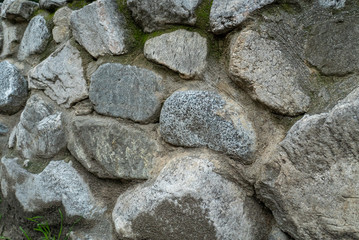 Detail of wall made of boulders with moss growing on overcast day