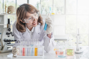 A young Asian woman scientist working in laboratory with test tube microscope and solutions.