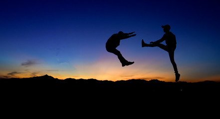 Silhouettes of two male fighters on sunset background.