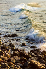 waves breaking with foam, on rocky shoreline