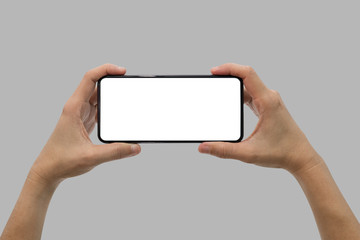 Hand holding black mobile phone with blank screen isolated on gray