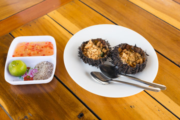 Cooked sea urchin on white plate in Vietnamese style and spice on another plate
