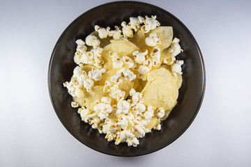Potato chips and Popcorn in a plate on white background