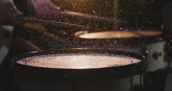 The drummer hit drum and water drops flying in all directions.