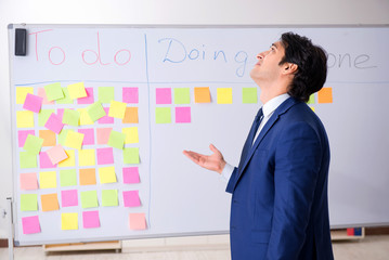 Young handsome employee in front of whiteboard with to-do list  