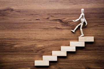 Stairs and wooden man model going down on wooden background. Business growth, steps to success or progress way to forward achievement concept.