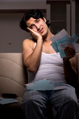 Fototapeta premium Young man calculating expences night at home 