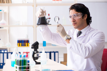 Young handsome chemist working in the lab 