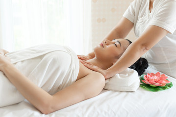Fototapeta na wymiar beautiful and healthy young Asian woman relaxing with face and shoulder massage at beauty spa salon
