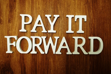 Pay It Forward alphabet letter on wooden background