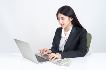 beautiful Asian business young woman working with laptop in office , Notebook  laptop and Us Dollars bill on white table office desk ,financial business concept