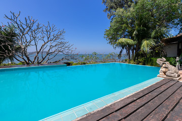 Swimming pool  blue water and tropical garden with sea view background