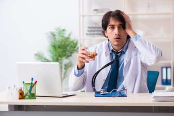 Young male doctor drinking in the office 