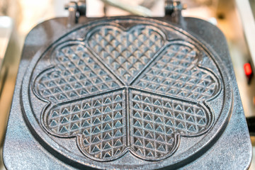 Close up empty waffle pan heart shape made from metal or cast iron or aluminum