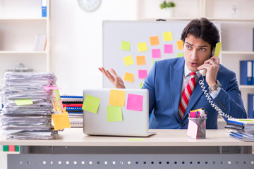 Young male handsome employee in conflicting priorities concept 