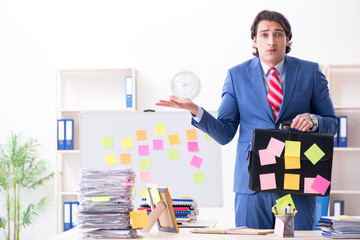 Young male handsome employee in conflicting priorities concept 