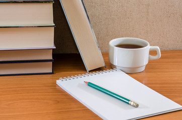 notebook, pencil, cup of tea and books on the table