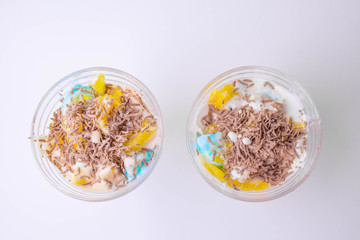 tasty homemade dessert in a sundae with colorful ice cream, fruit, chocolate chips on a white background for children and adults.