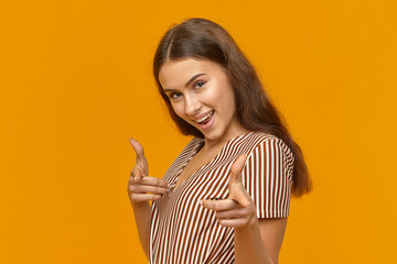 Isolated shot of cute beautiful girl with long loose hair smiling excitedly and pointing index...