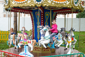 Fototapeta na wymiar a little girl on a children's carousel in the city Park