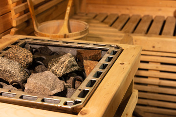 Empty wooden traditional sauna room.Hot stone, wooden bucket with accessories in the spa room.Selective focus