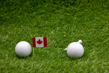 Golf ball with flag of Canada are on green grass