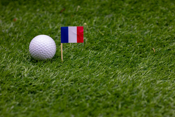 Golf ball with flag of France on green grass