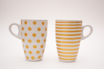 Two cups of coffee stand together. Cups for coffee with a pattern in the form of circles and stripes on a white background. Layout, copy space.