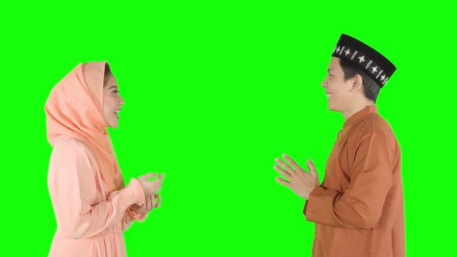 Happy muslim couple giving a greeting hands gesture for forgiving each other in the studio. Shot in 4k resolution with green screen background