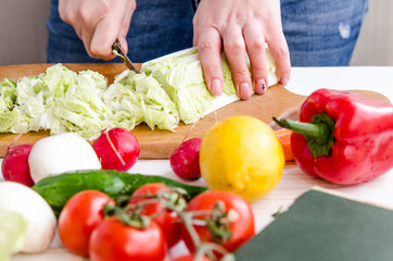 Woman hands cutting vegetables on wooden background