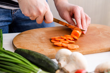 Woman hands cutting vegetables on wooden background