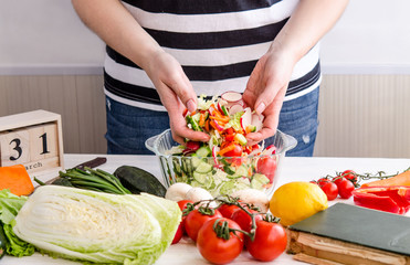 Woman hands adding vegetables to dishes