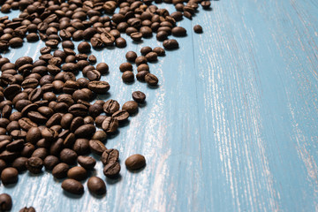 Roasted coffee beans in bulk on a blue wooden background. dark cofee roasted grain flavor aroma cafe, natural coffe shop background, top view from above, copy space