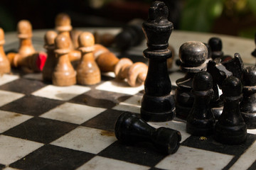 Obraz premium Outdoor stone chessboard with black and yellow figures. Competition and strategy concept. Intelligent sport. Defeat and fight concept. Chess wooden pieces on board in sunlight. Summer leisure.