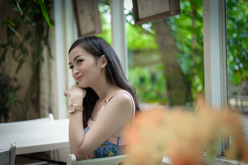 Naklejka premium Asian pretty girl has relaxing with happy and smiling at Little Tree Garden cafe, Nakhon Pathom province, Thailand in the morning.