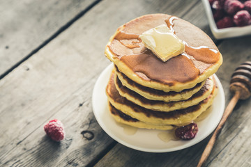 Sweet Homemade Stack of Pancakes with Butter, raspberryes and Honey for Breakfast