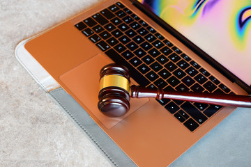 Judge gavel on rose gold color laptop computer. Concept of online auction, cyber crime, law system.