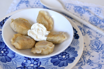 Dumplings pierogi on a plate with sour cream