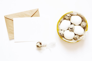 Blank greeting card, kraft envelope. Easter composition with easter eggs and feathers on white background. Image