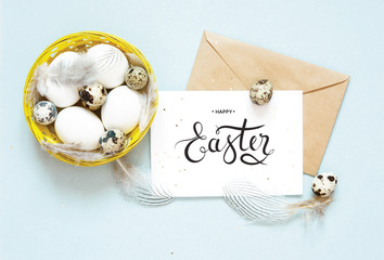 Inscription Happy Easter, kraft envelope. Easter composition with easter eggs and feathers. Flat lay, top view.