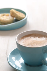 Coffee in turquoise cup with lemon muffins in background