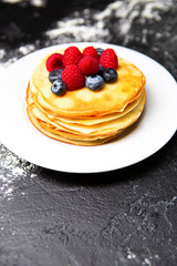 Photo of plate with pancakes, blueberries, raspberries dusted with icing sugar