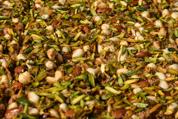 Turkish dessert with nuts and honey, pistachios, almonds and peanuts in soft focus at a food market