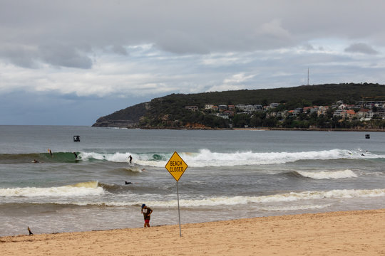 Surfeur sur la plage de Manly &agrave; Sydney &agrave; c&ocirc;t&eacute; d'un panneau interdisant la baignade